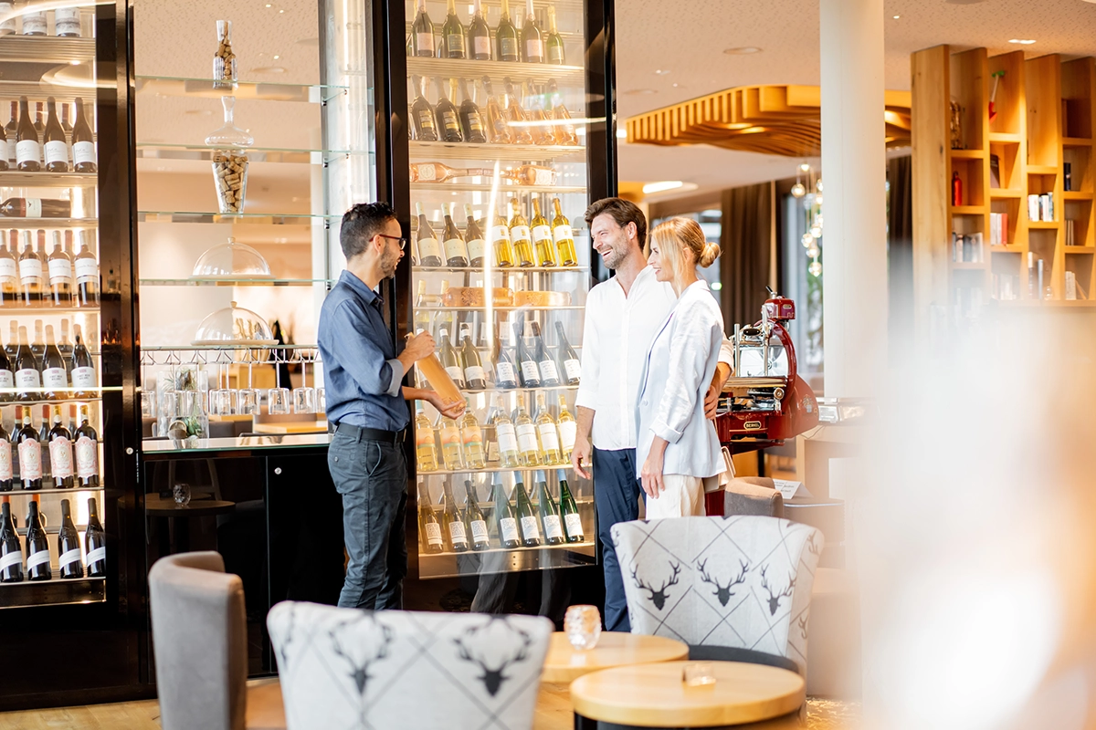 Ein Mann und eine Frau werden vom an der Hotelbar vom Kellner über das Weinangebot beraten