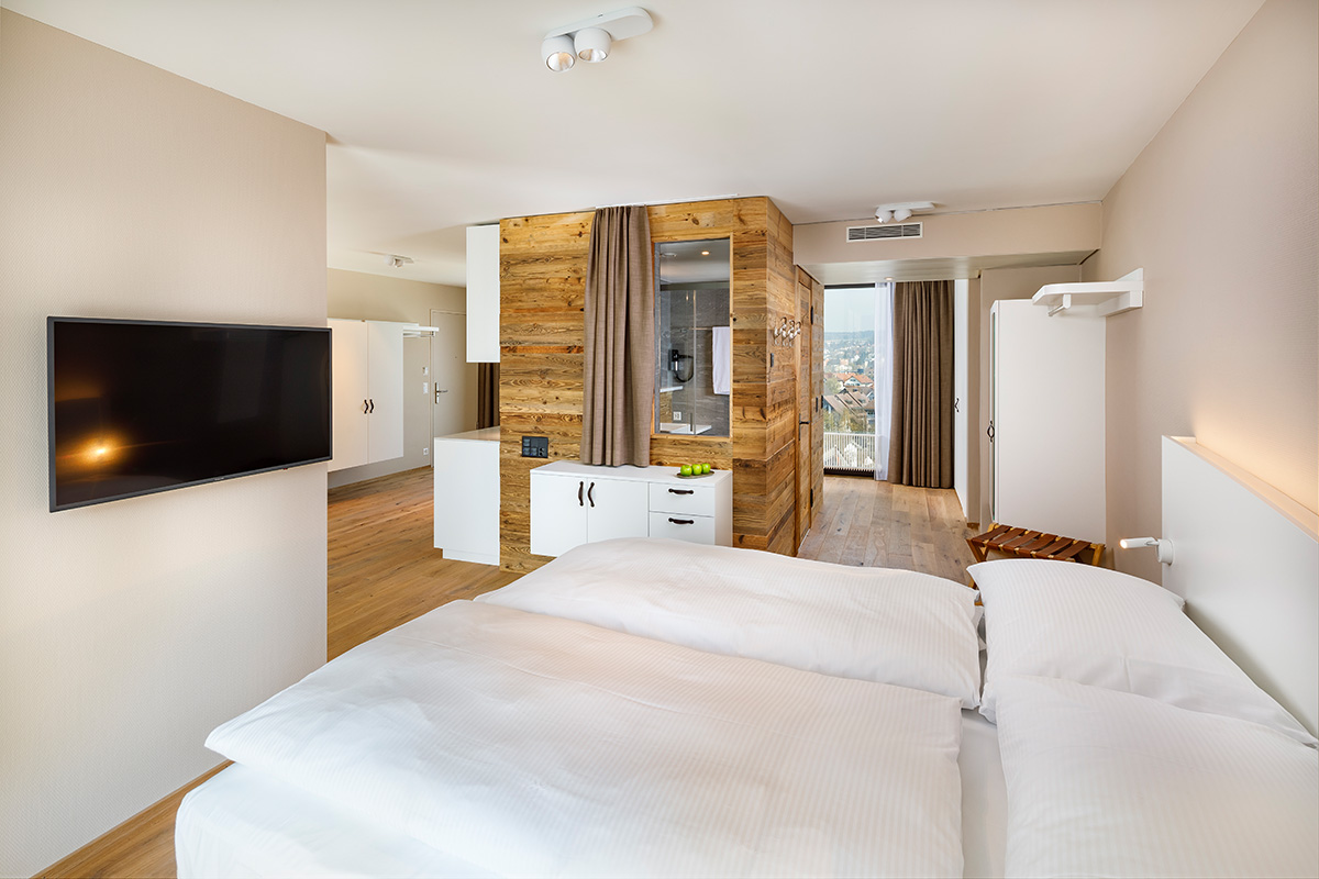 Grosses Apartment in der Allegra Lodge Kloten mit Doppelbett, separatem Wohnbereich, Sofabett, Kueche und modernem Parkettboden.