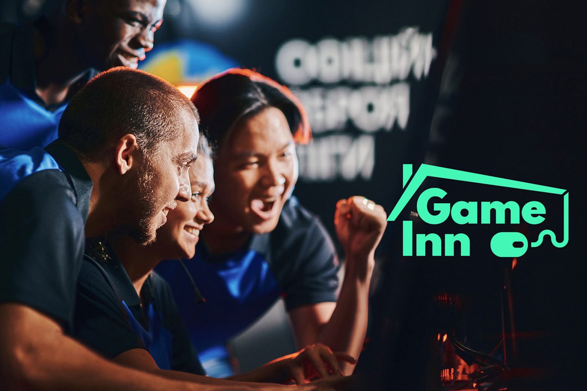 Vier Freund sind am Gamen vor einem PC, dunkler Hintergrund, im Vordergrund Bildlogo Game INN