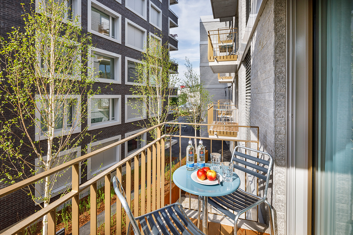 Privater Balkon der Allegra Lodge Serviced Apartments in Kloten mit Sitzgelegenheit und Blick auf den modernen Innenhof.