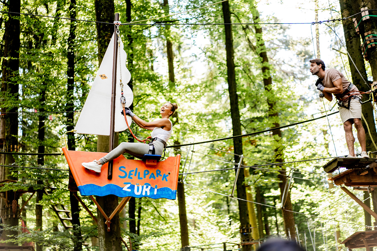 Eine Frau und ein Mann klettern eine Route im Seilpark Zurich, nah an der Allegra Lodge in Kloten.
