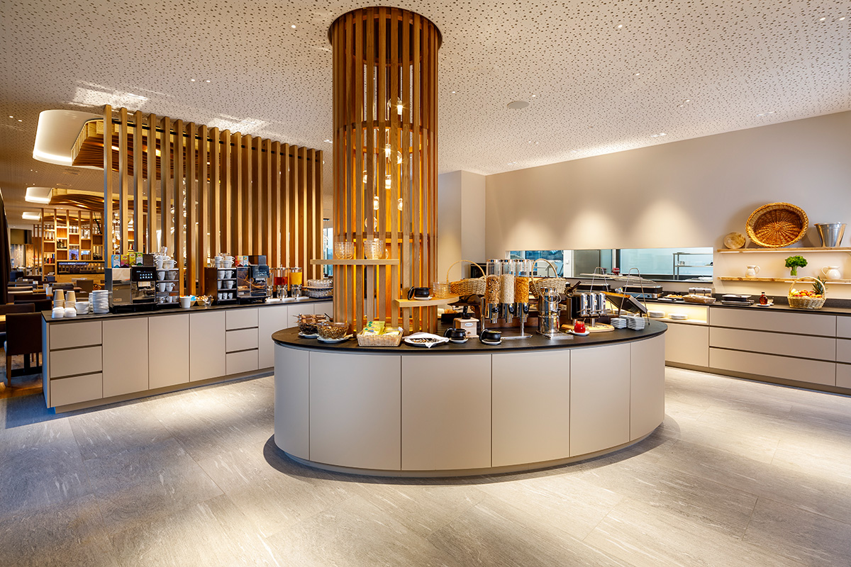 Modern breakfast area at Allegra Lodge featuring a circular buffet island and a professional coffee station.