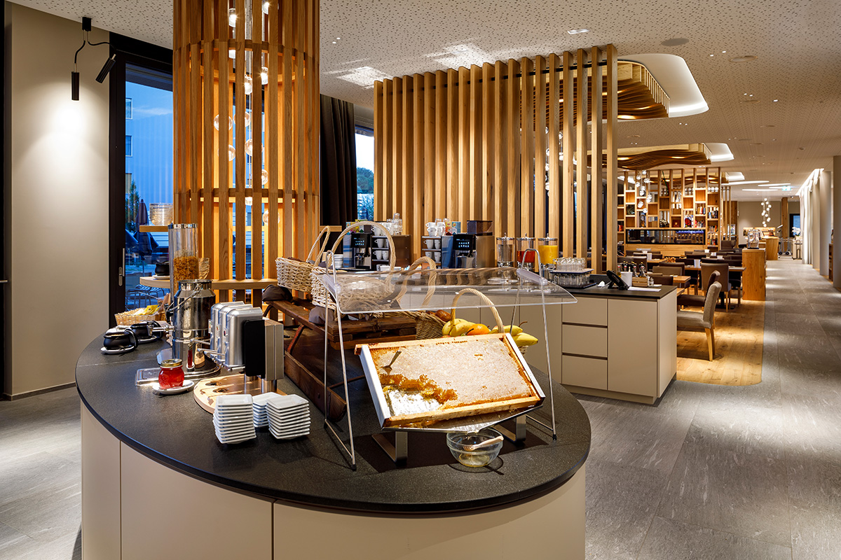 Detailed view of the breakfast buffet with a fresh honeycomb and a warm-lit wooden louvered column.