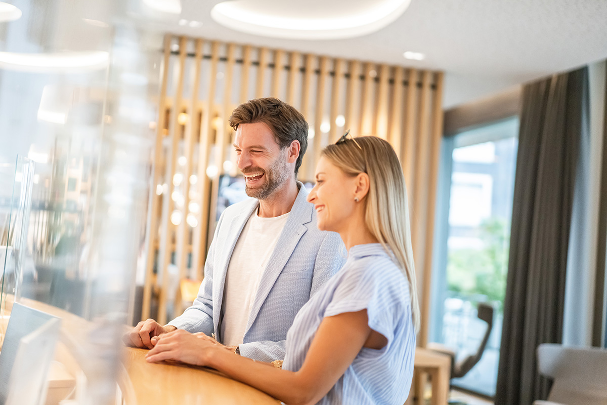 Junges Paar steht an der Rezeption in der Allegra Lodge und checkt ein.