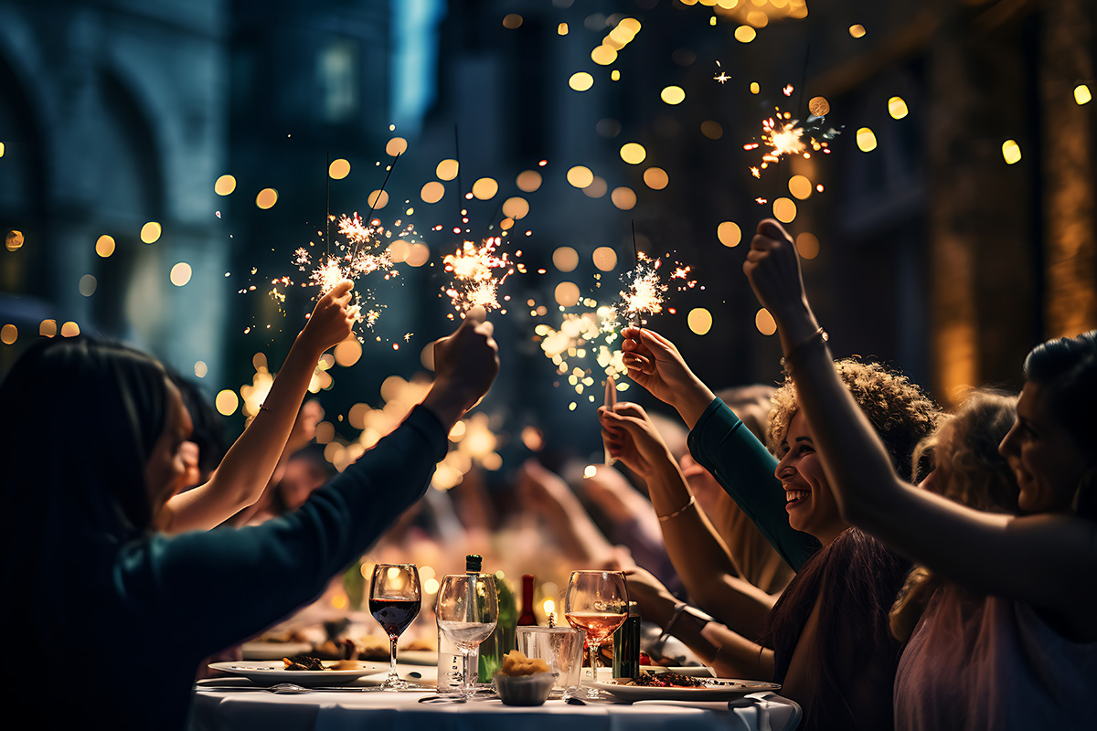 People sitting at a table, celebrating and holding sparklers in the air.
